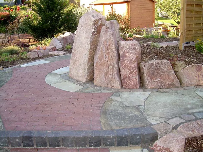 Handverlesener Naturstein-Monolith als Solitärelement auf kreisförmiger Pflasterfläche