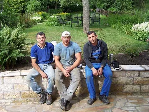 Fachkräfte der Krasniqi Garten- und Landschaftsbau GmbH auf einer präzise errichteten Natursteinmauer